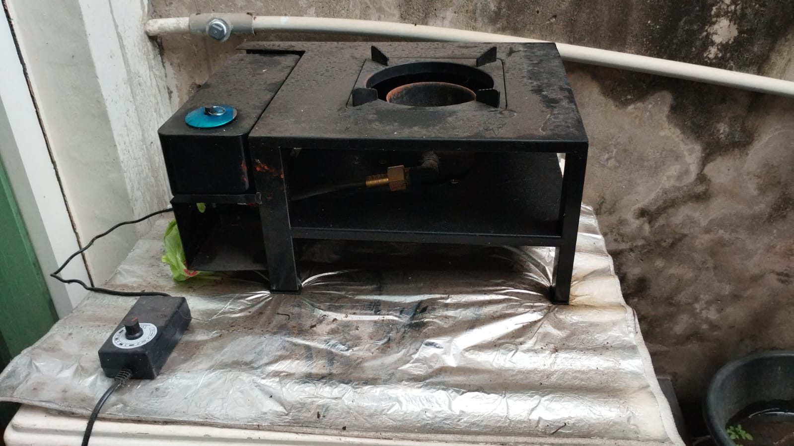 Kompor berbahan bakar oli bekas dengan rangka besi dan unit kendali aliran bahan bakar